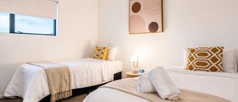 Una camera d'albergo con due letti, un comodino con una lampada e una finestra con persiane.