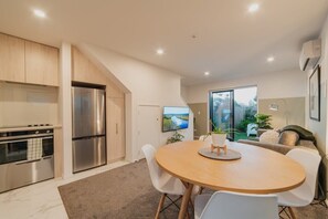 Enjoy meals in the kitchen with stainless steel appliances, a dining area with a round table and chairs, and a TV for entertainment.