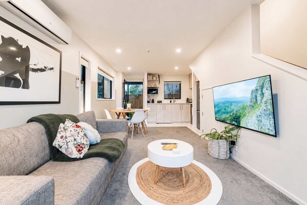 A modern living room with a sofa, coffee table, and a TV mounted on the wall.
