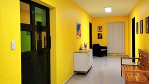 A bright hallway with yellow walls, a white cabinet, a wooden bench, and a door with a black frame. - Jenessa's Executive Suite 90 sqm near Lanuza Surf Bay (Madrid)
