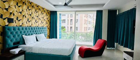 A modern bedroom with a large bed, a red chair, and a ceiling fan.