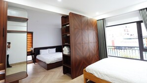 A modern hotel room with a large bed, a wardrobe with a geometric pattern, a mirror, and a window with a view of buildings. - Smile Homestay (Hue)