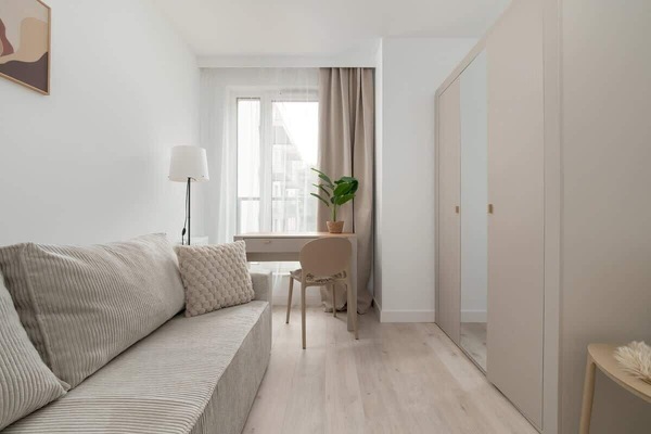 Bedroom with soft sofa, bright decor, and natural light access is perfect for relaxing.