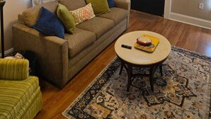 Un salon avec un canapé, une petite table, une lampe et un tapis à motifs.
