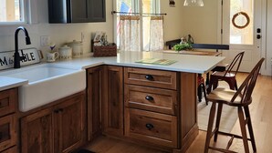A kitchen with wooden cabinets, a white countertop, and a large island with a sink. - Charming 3-bedroom farmhouse on 20 acres located in rustic Corbin City.  (Corbin City)