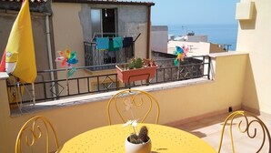 Una mesa y sillas amarillas en un balcón con vista al mar.