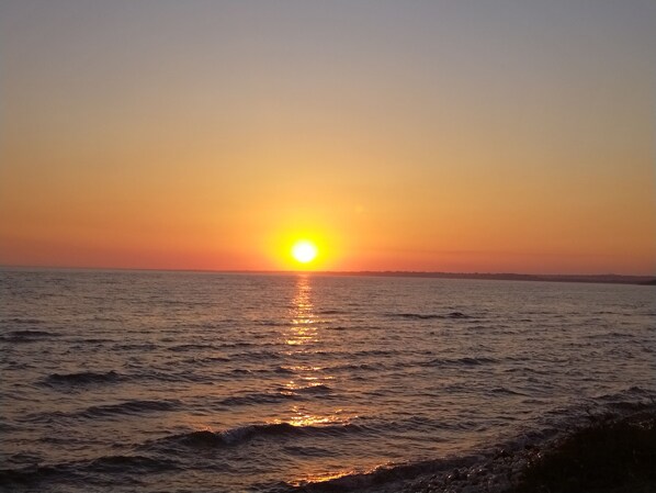 Un coucher de soleil sur une mer calme, avec un horizon dégagé.