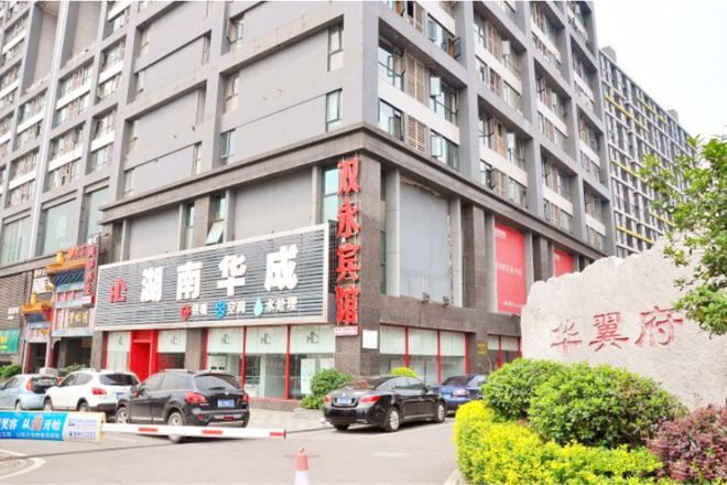 Un edificio de varios pisos con un local comercial en la planta baja, que presenta un letrero con caracteres chinos.