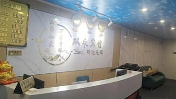 A reception desk with a marble wall and a ceiling with a light fixture.