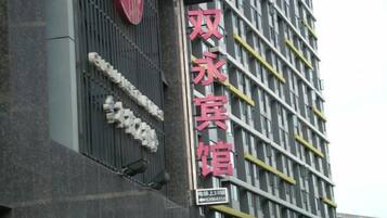 A building with a large sign in red characters, a modern architectural design, and a series of windows.