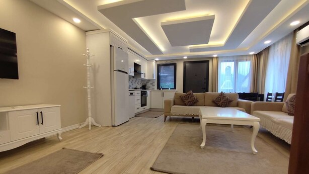 A modern living room with a sofa set, a coffee table, and a TV mounted on the wall. - Garden House Uzungöl (Çaykara)