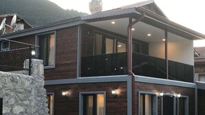 A two-story house with a balcony, stone foundation, and multiple windows. - Garden House Uzungöl (Çaykara)