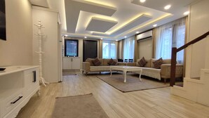 A modern living room with a sofa set, a coffee table, and a TV. - Garden House Uzungöl (Çaykara)