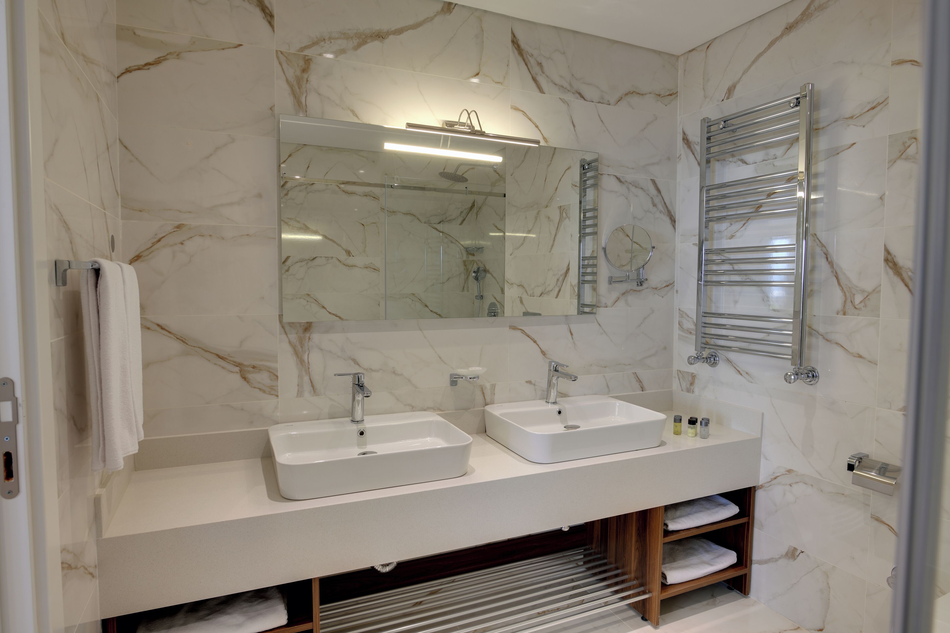 Un baño moderno con dos lavamanos, un espejo grande y un perchero para toallas.