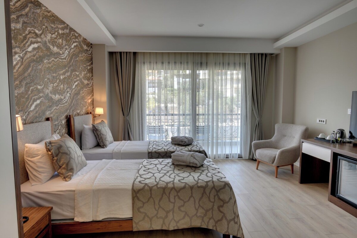 A hotel room with two beds, a desk, a chair, and a TV.