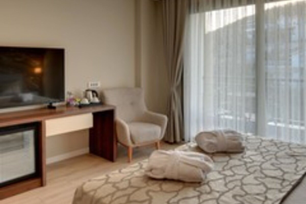Una camera d'albergo con un letto, una scrivania, una sedia e una televisione.