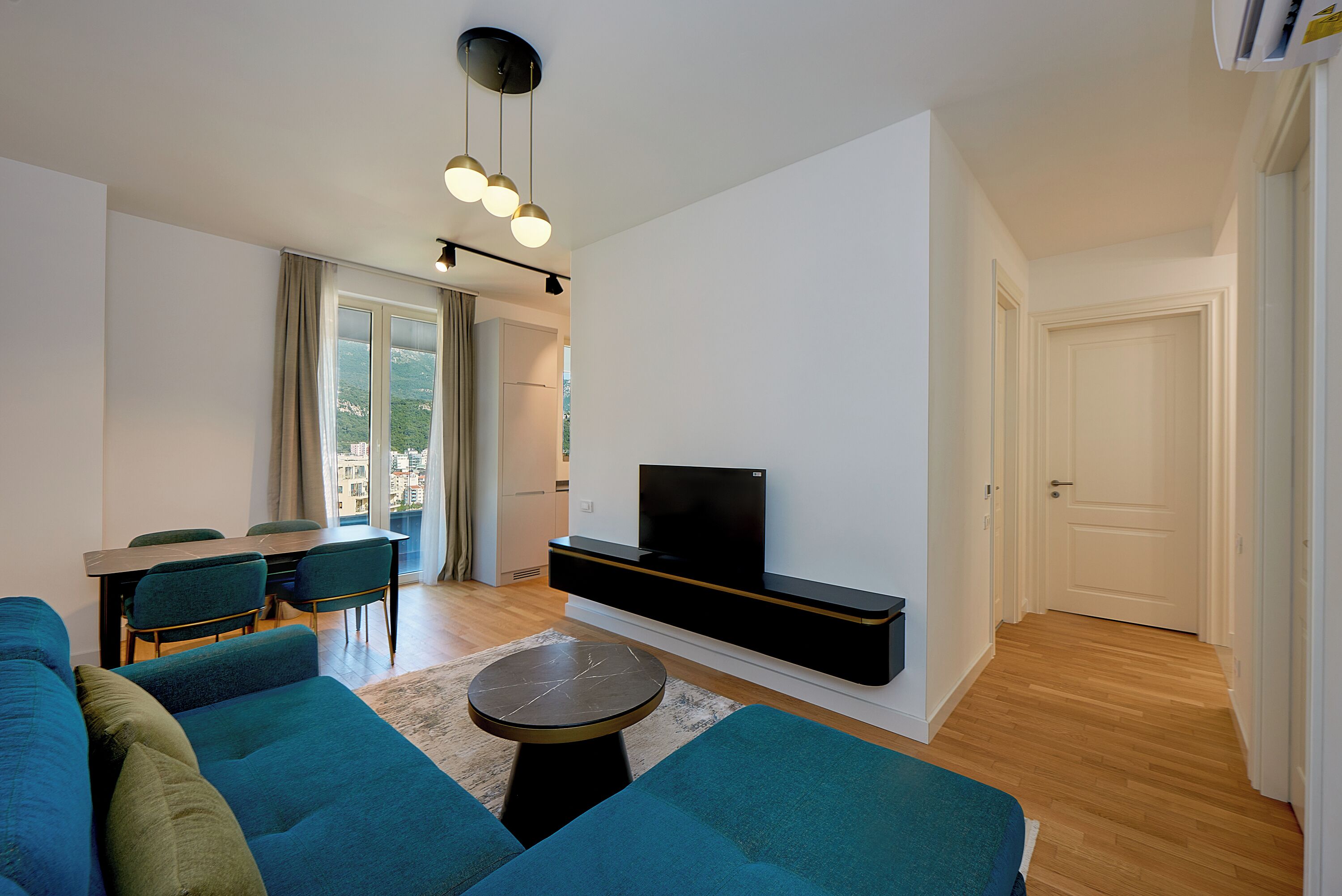 Una sala de estar moderna con un conjunto de sofá, una mesa de comedor y un televisor de pantalla plana montado en la pared.