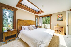 Relax in this serene retreat with a large bed, nightstand, and dresser, surrounded by a view of lush greenery.