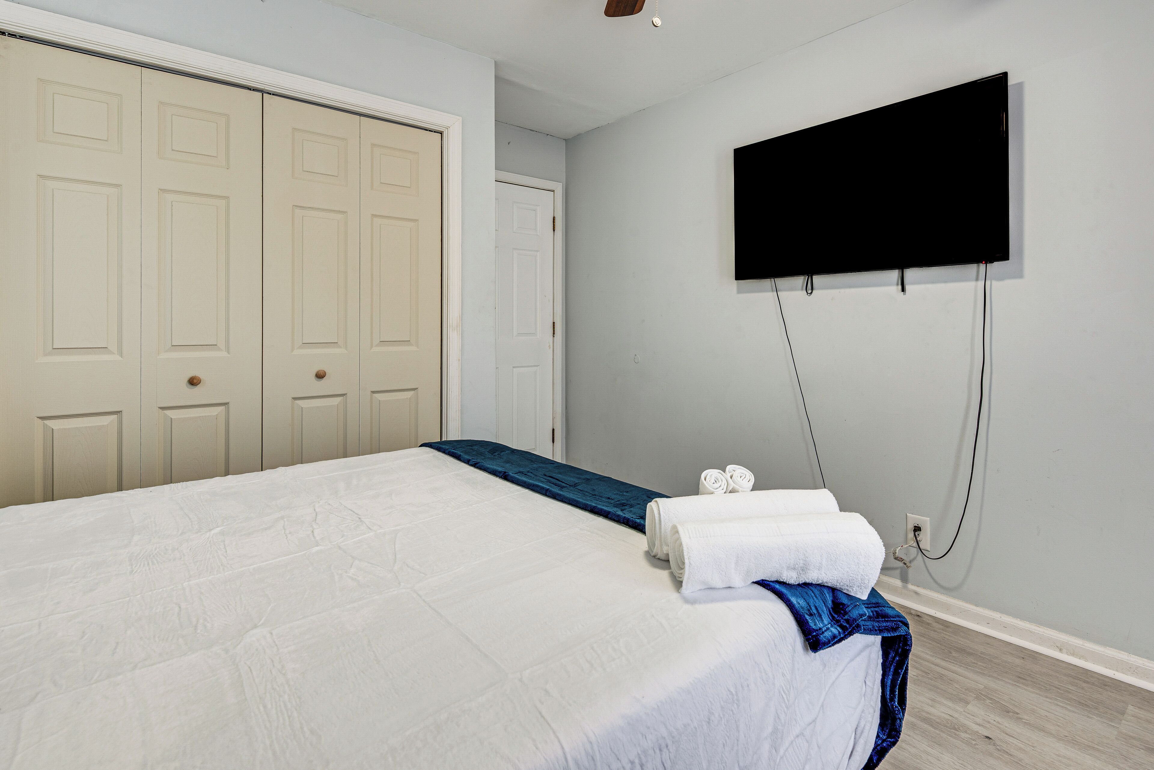 Une chambre à coucher avec un lit, un téléviseur fixé au mur et une armoire avec des portes.