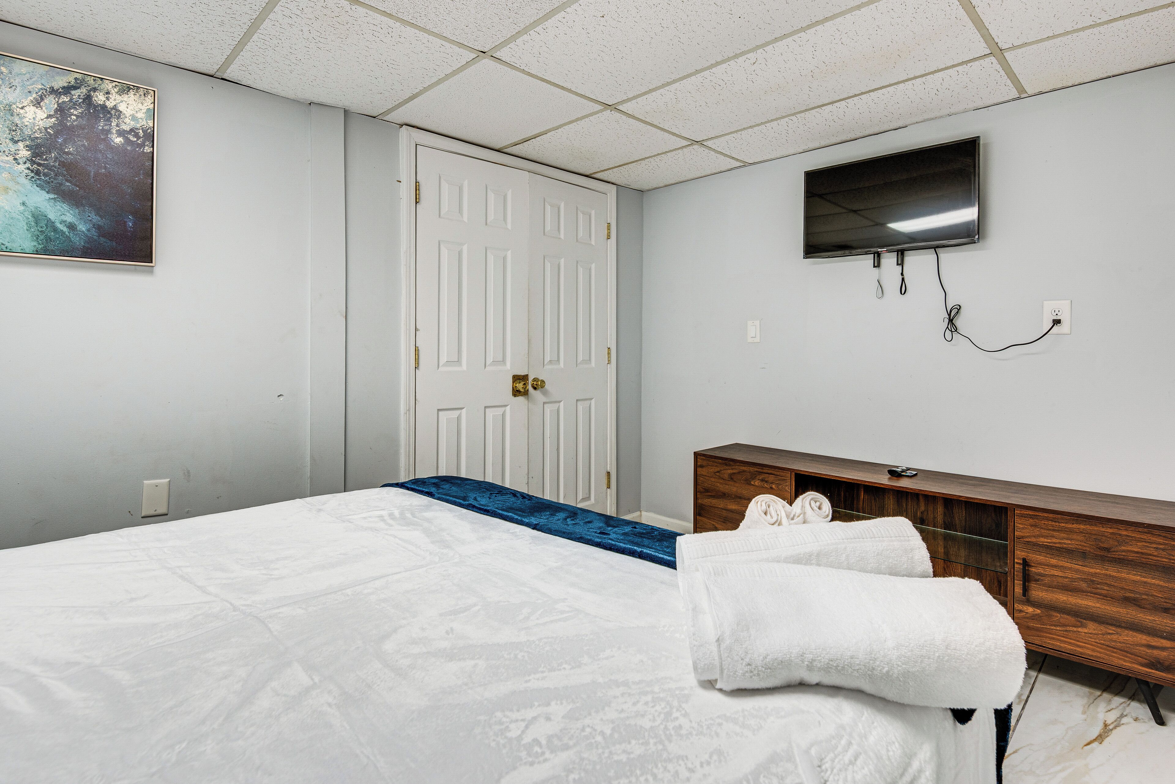 A hotel room with a bed, a wooden dresser, a flat-screen TV, and a door.