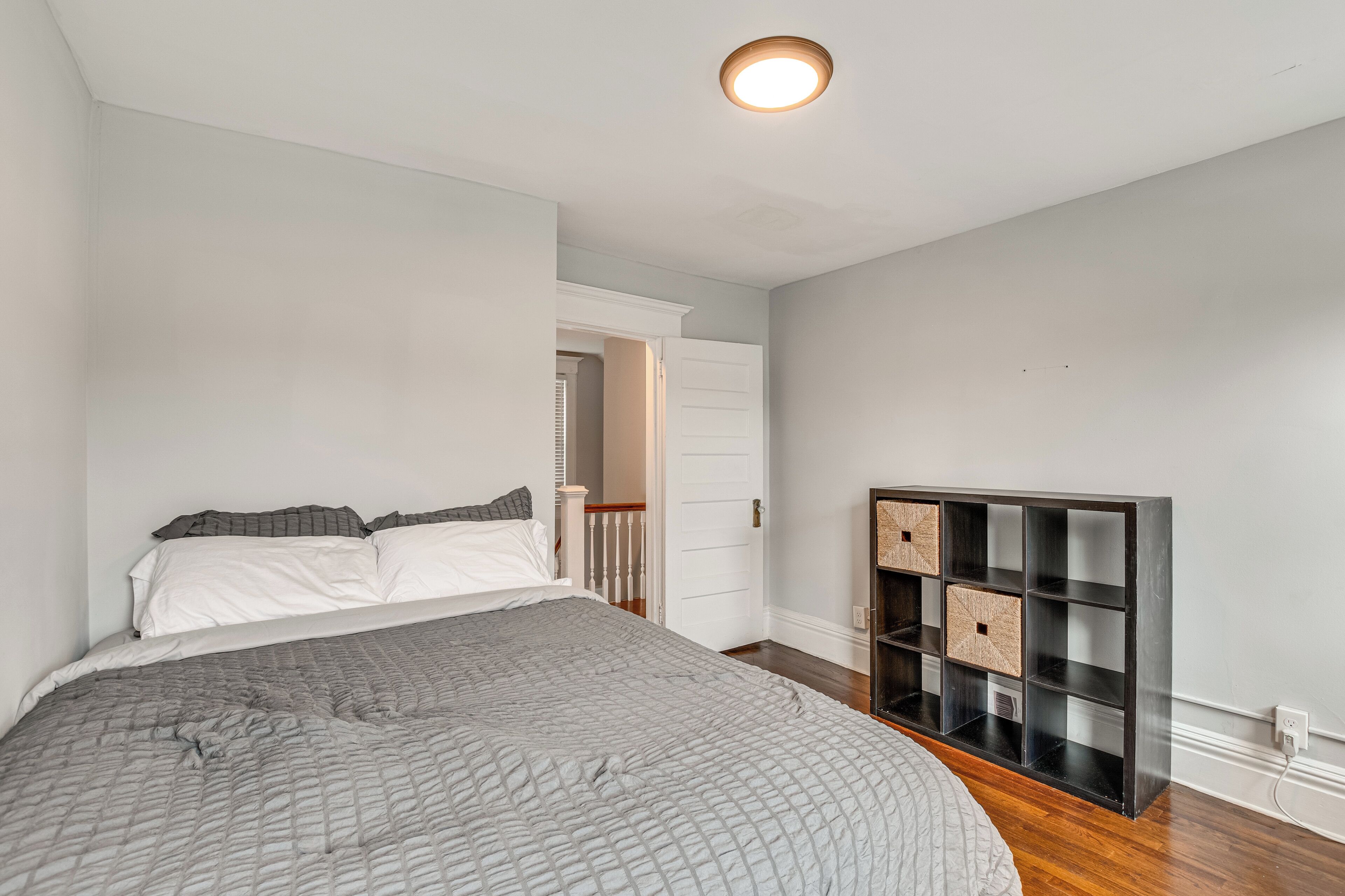 Une chambre à coucher comprenant un lit, une table de chevet, une commode et une bibliothèque intégrée.
