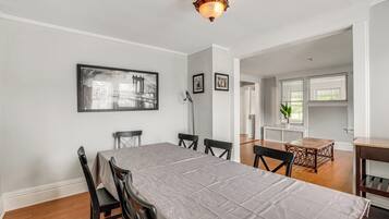 A dining room with a long table, chairs, a chandelier, and framed pictures on the wall.