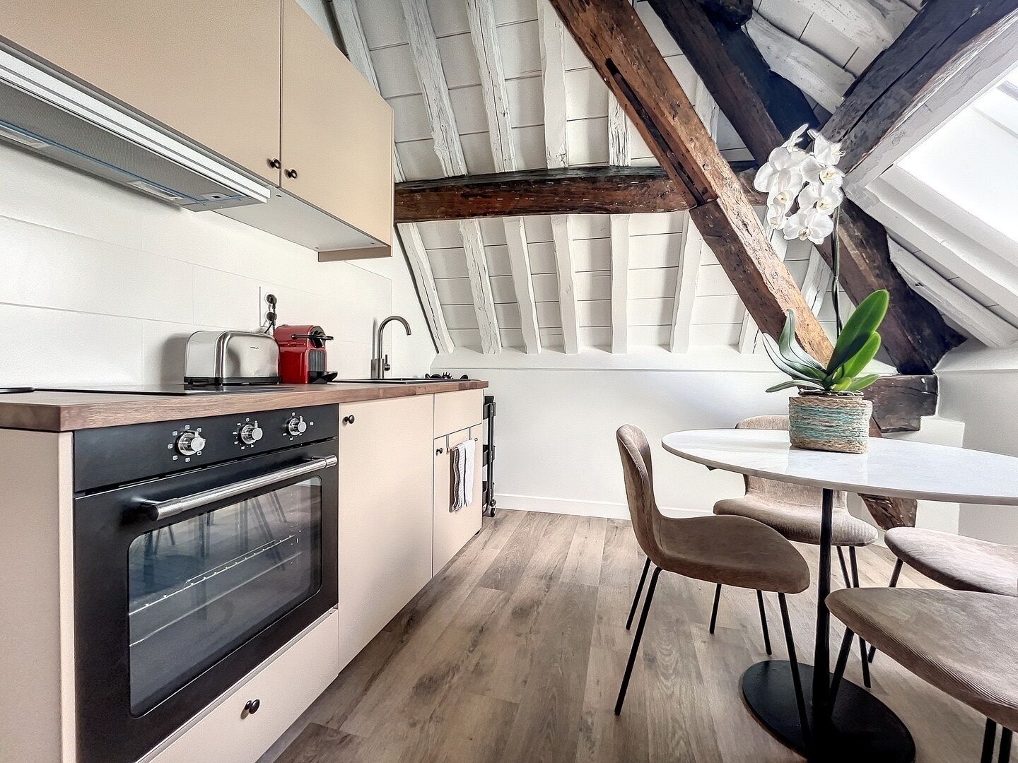 A modern kitchen with a wooden countertop, a built-in oven, and a dining area with a round table and chairs.