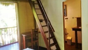 Een kamer met een houten wenteltrap naar een hoger niveau, een bed, een klein tafeltje en uitzicht op de omgeving.