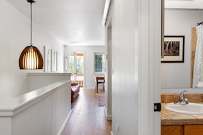 Stylish hallway leads to a bathroom with a white sink, large mirror, and framed artwork.
