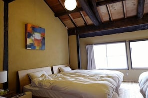 Quarto com cama, mesa de cabeceira, um quadro e janela.