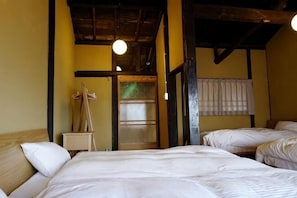 A room with a bed, a wooden headboard, a hanging light fixture, and a window with a curtain. - Honmachi-Shin North (Kyoto)
