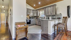 A modern kitchen with wooden cabinets, a central island, and a dining area with a chair.