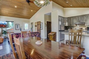 A spacious dining area with a wooden table and chairs, a kitchen with modern appliances, and a ceiling fan. - 5BD – Large Yard & Firepit | Escape to the Mtns! (Cascade-Chipita Park)