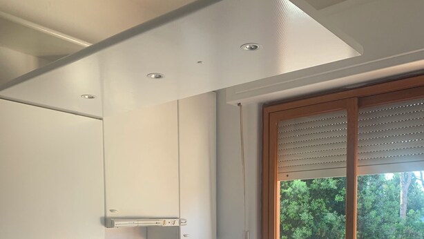 A modern kitchen with white cabinets, a gas stove, and a window with blinds. - Charming 2-bedroom condo with AC, WiFi just Steps from the Beach (Anzio)
