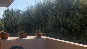 A round table with chairs, potted plants, and a cabinet on a balcony. - Charming 2-bedroom condo with AC, WiFi just Steps from the Beach (Anzio)