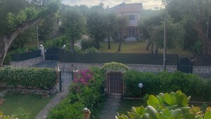 A residential property with a stone wall, a gated entrance, and a well-maintained garden. - Charming 2-bedroom condo with AC, WiFi just Steps from the Beach (Anzio)