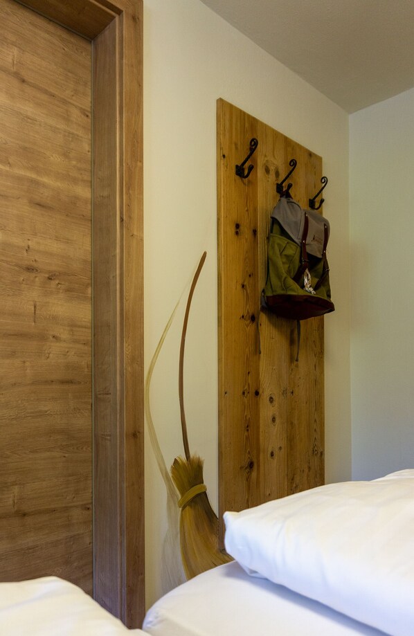 A wooden wall with a coat rack holding bags and a broom. - Alpengasthof Hochsöll  (Soell)