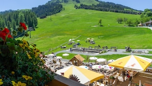 A view of a green field with a wooden structure and a small building in the distance. - Alpengasthof Hochsöll (Soell)