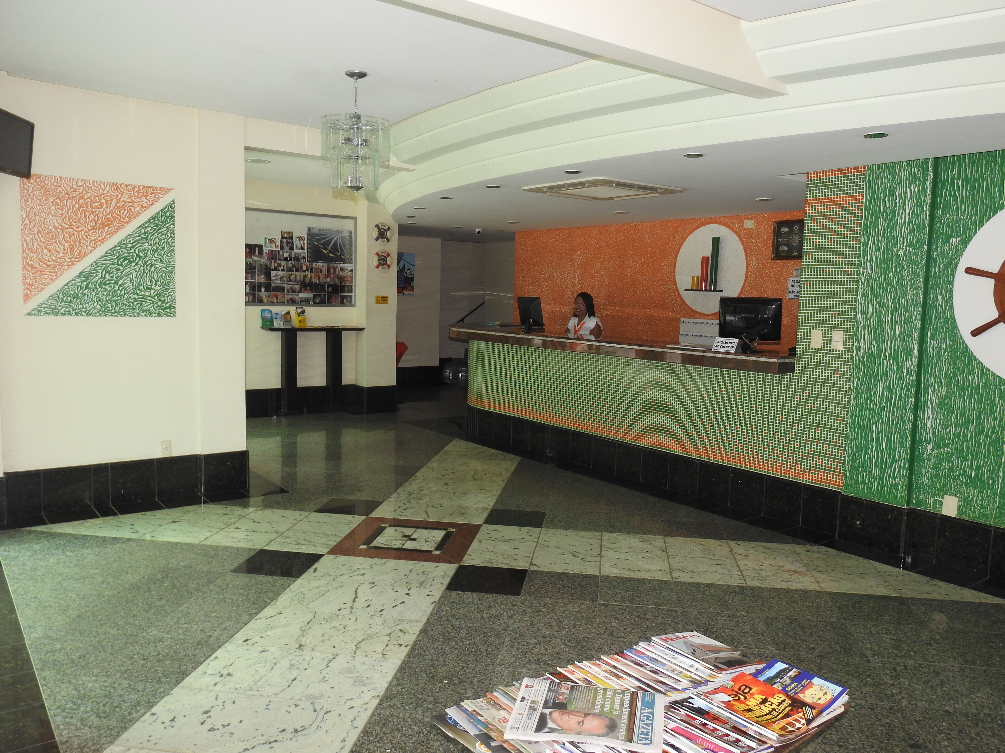 A reception area with a counter, a woman behind it, and a wall with a circular design.