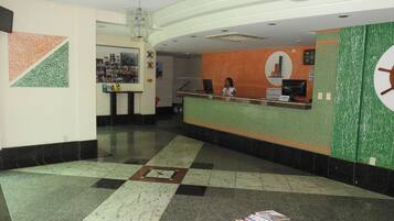 A reception area with a counter, a woman behind it, and a wall with a circular design.
