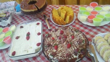 Taula amb diferents postres, com un pastís, una tarta i un plat de cupcakes.