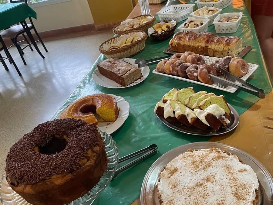 Una mesa de buffet con diversos postres y pasteles, incluyendo un pastel bundt de chocolate, una tarta y varias bandejas de rosquillas.