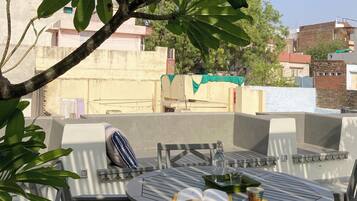 Relax in this serene outdoor seating area with a round table and two chairs, surrounded by lush greenery and a potted plant.