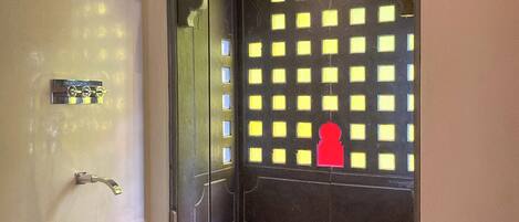 Un baño moderno con cabina de ducha de vidrio, un secamanos visible y una escultura decorativa de un pez en el suelo.