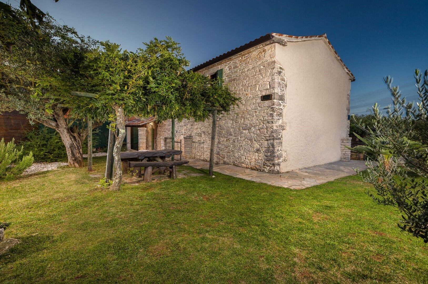 Un bâtiment rustique en pierre, doté d’un petit porche et d’une table de pique-nique.
