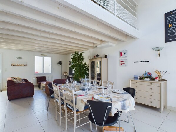 A dining area with a table set for four, surrounded by chairs, a cabinet, and a plant.