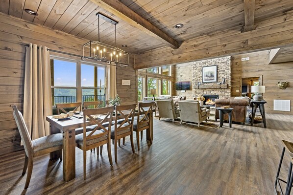 Un intérieur rustique en bois, avec un coin repas, une cheminée et un mur en pierre.
