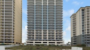 Un hôtel à plusieurs étages, doté d’une façade incurvée, de balcons et d’un parking situé à sa base.