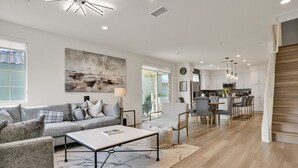Ein modernes Wohnzimmer mit Sofa, Couchtisch und Essbereich mit Stühlen.