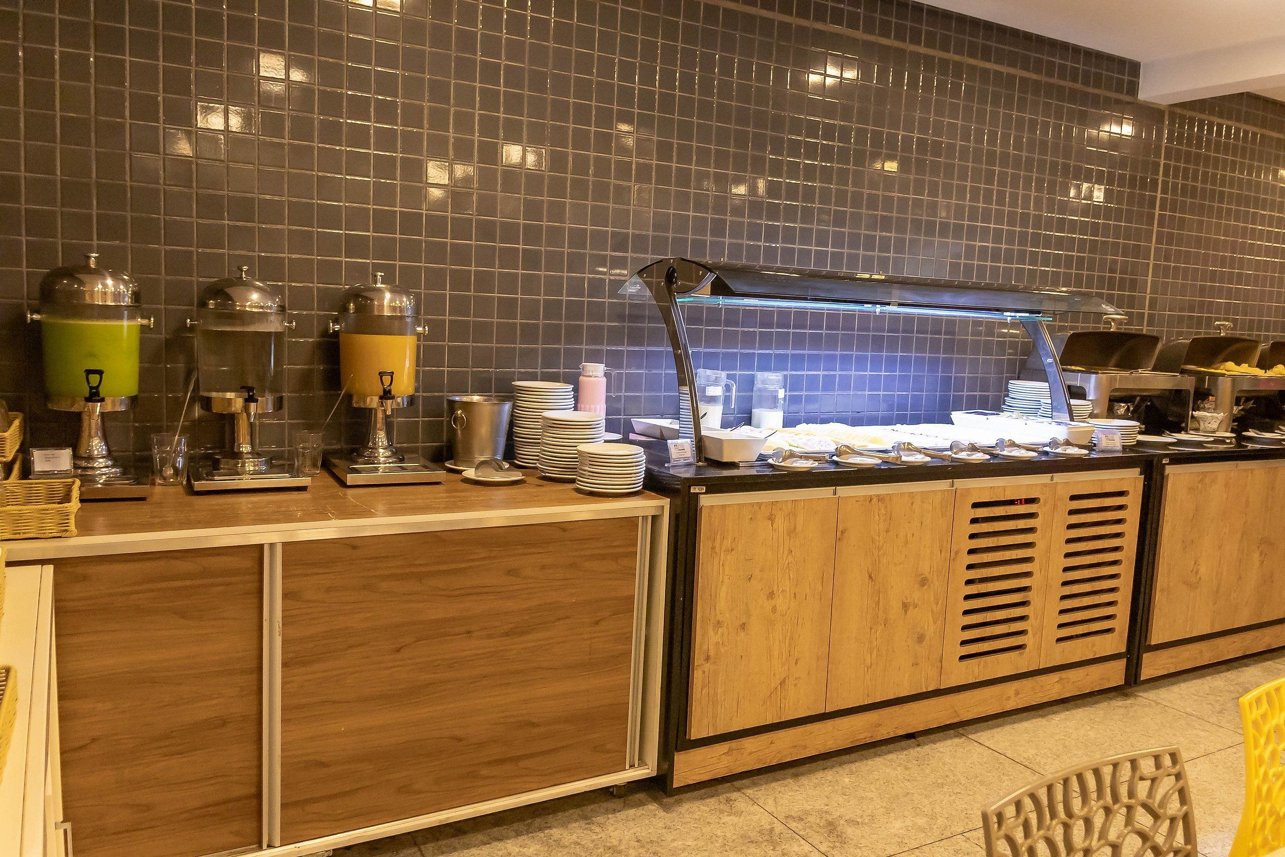 A buffet setup with food dispensers, plates, and a glass display case.